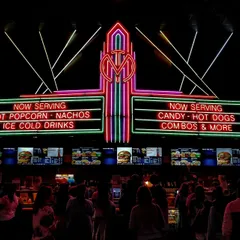 A neon cinema concession sign glowing over a busy counter